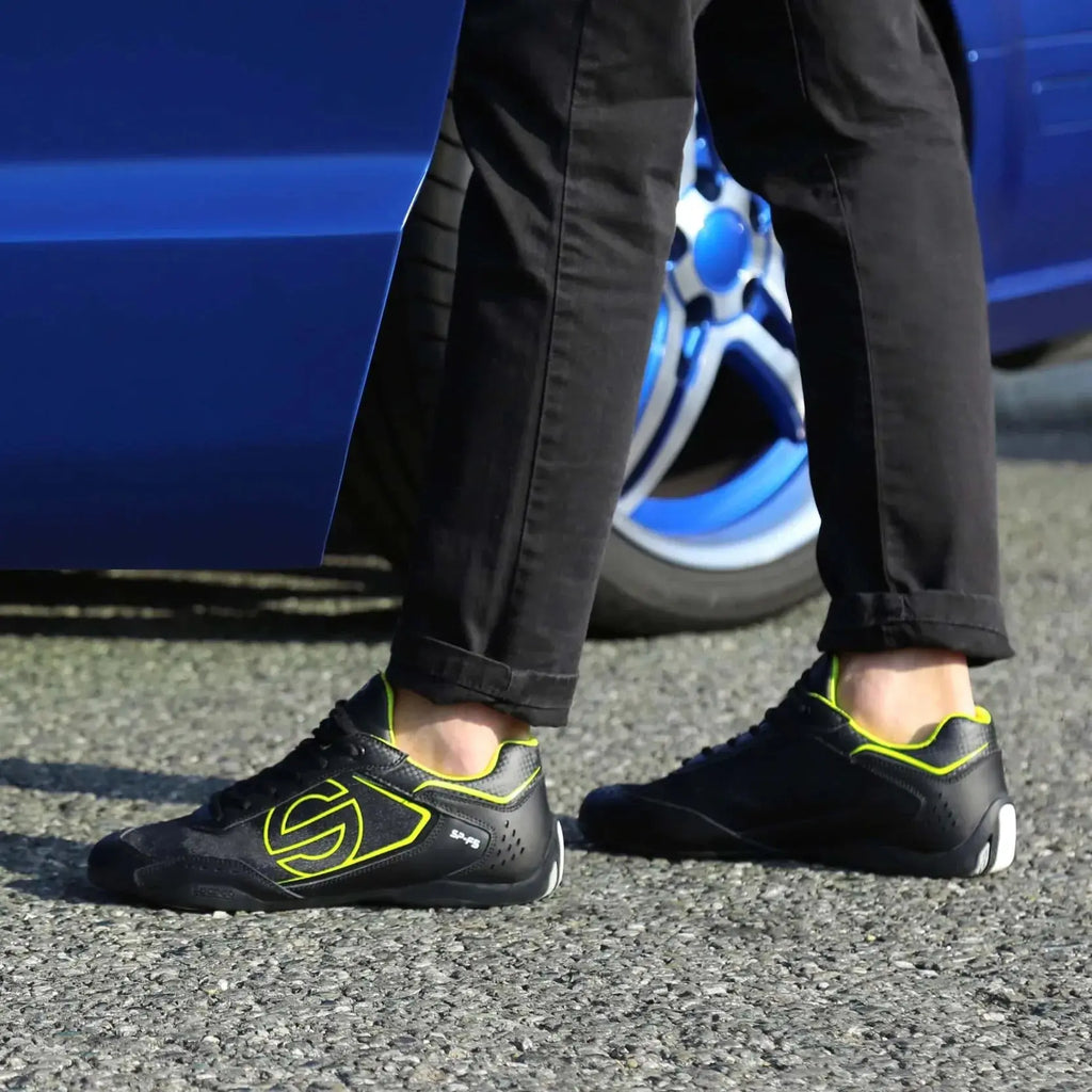 Paire de Sneakers Sparco SP-F5 noir et jaune, empiècement effet carbone, semelle noire qui remonte sur le talon, gros logo S fluo sur le côté, portée