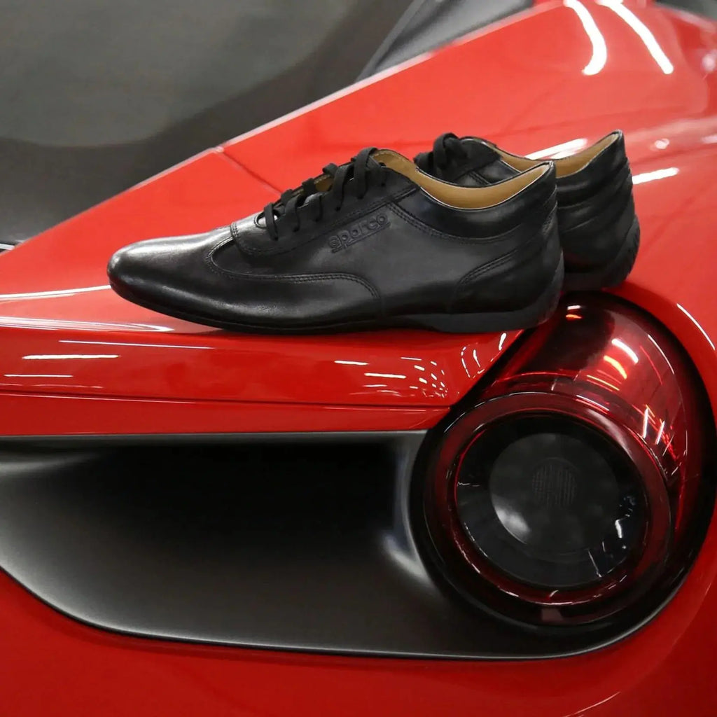 Paire de Chaussure Sparco Imola en cuir noir, made in Italy, posée sur Ferrari
