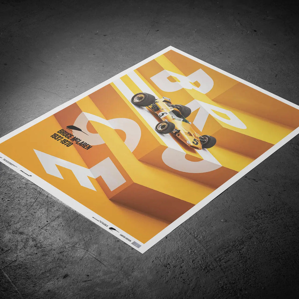 Affiche Automobilist jaune de la McLaren Papaya de Bruce McLaren modélisée en 3D sur un escalier avec le lettrage Bruce en blanc posée au sol