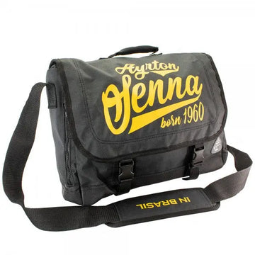 Sac Messager noir portant l'inscription Ayrton Senna Born 1960 en jaune sur le rabat fermé par 2 boucles en plastique avec poignée sur le dessus et bandoulière portant in Brasil en jaune de 3/4 