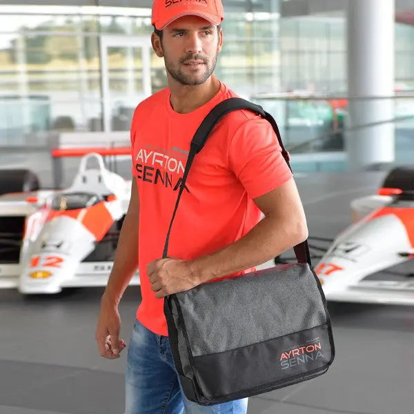 Sac Messager noir et gris portant l'inscription Ayrton Senna McLaren sur le rabat et bandoulière porté devant des F1