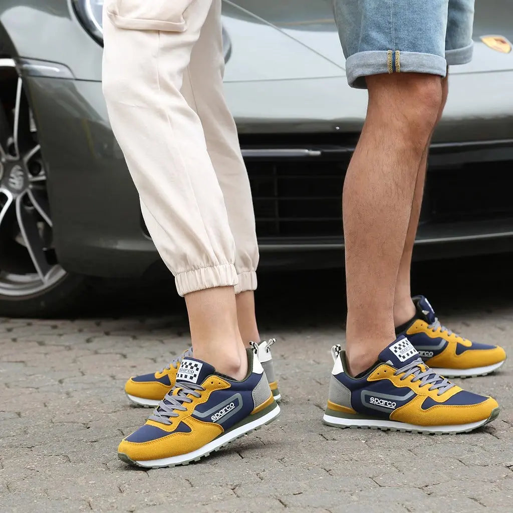 2 paires de Sneakers Sparco Flag jaune bleu et gris style streetwear au look vintage, portées par un couple